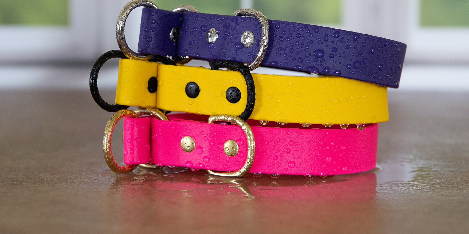 Stack of three waterproof BioThane slip collars in purple, yellow, and bubblegum pink with brass hardware