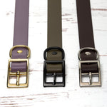 Three collars with gold, black, and silver hardware on a white wooden surface