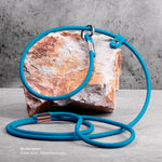 Ocean blue slip lead with silver hardware, lying on a rock on a white background, with product description
