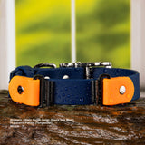 A BioThane deep sea blue water-resistant buckle collar with tangarine colored accents and silver hardware, shown on a wet log with a blurred green background. Text at the bottom reads: 'Primary - Main Collar Color (Deep Sea Blue) Flapless Pieces (Tangerine) Width - 1.