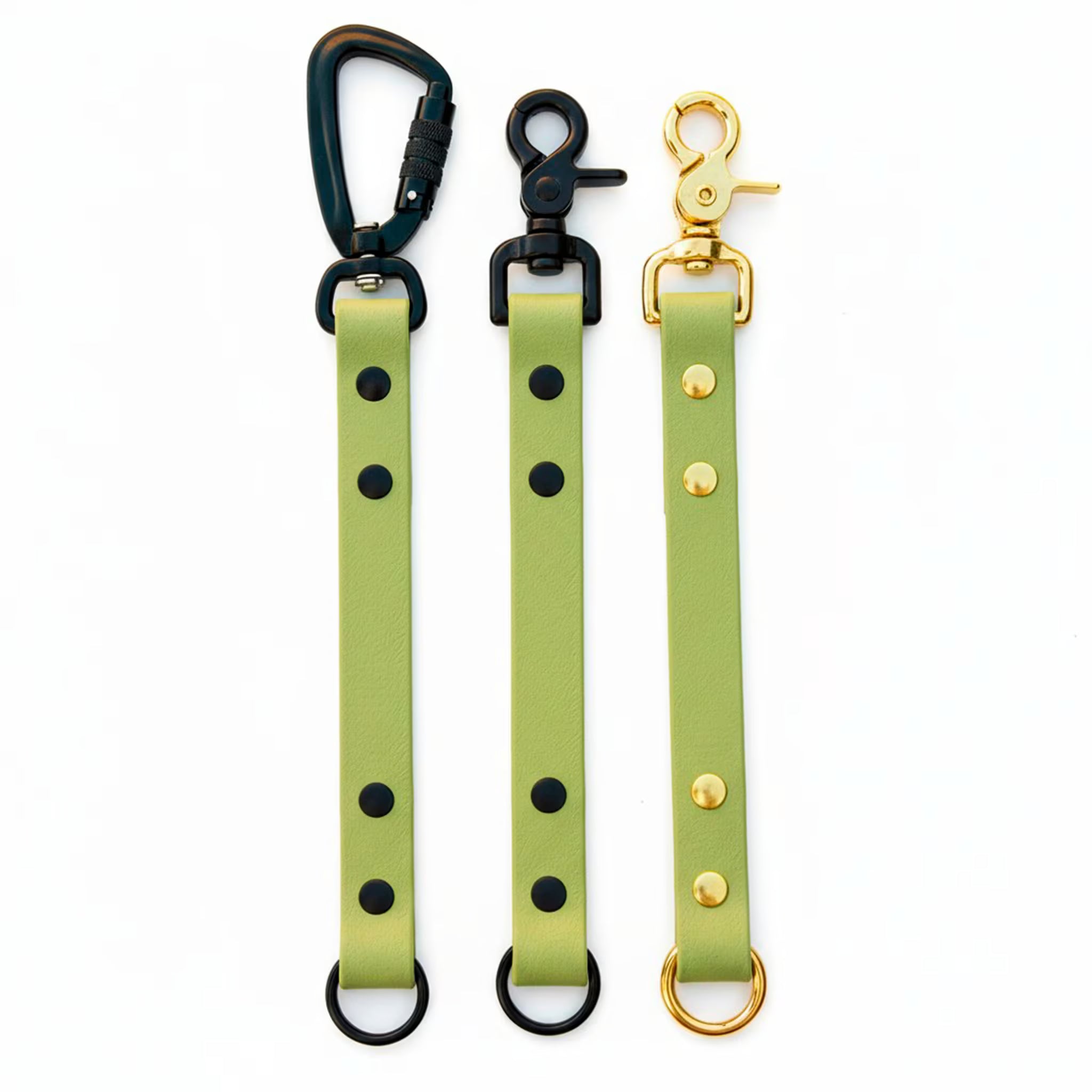 Biothane training tabs shown pictured with matte black carabiner, matte black trigger snap and solid brass trigger snap on a white background.